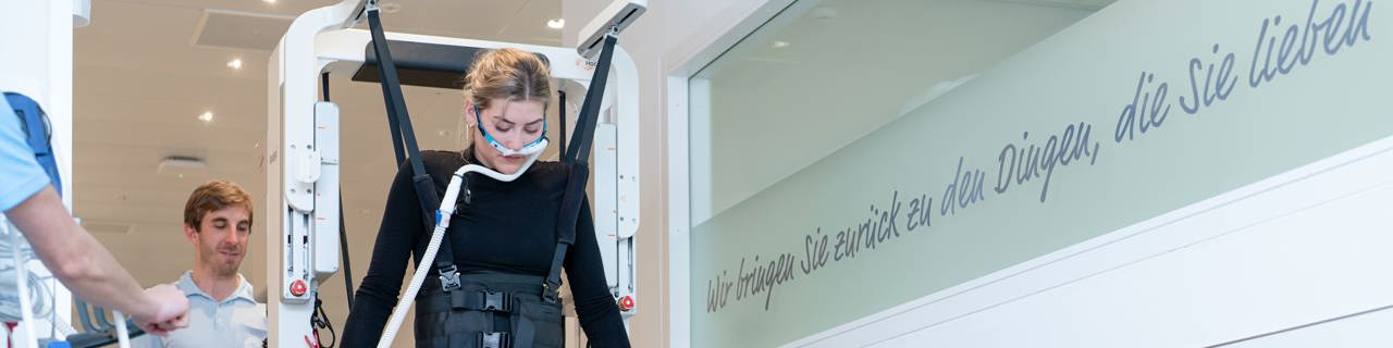 Frührehabilitationspatientin zusammen mit Physiotherapeuten während der Gangtherapie